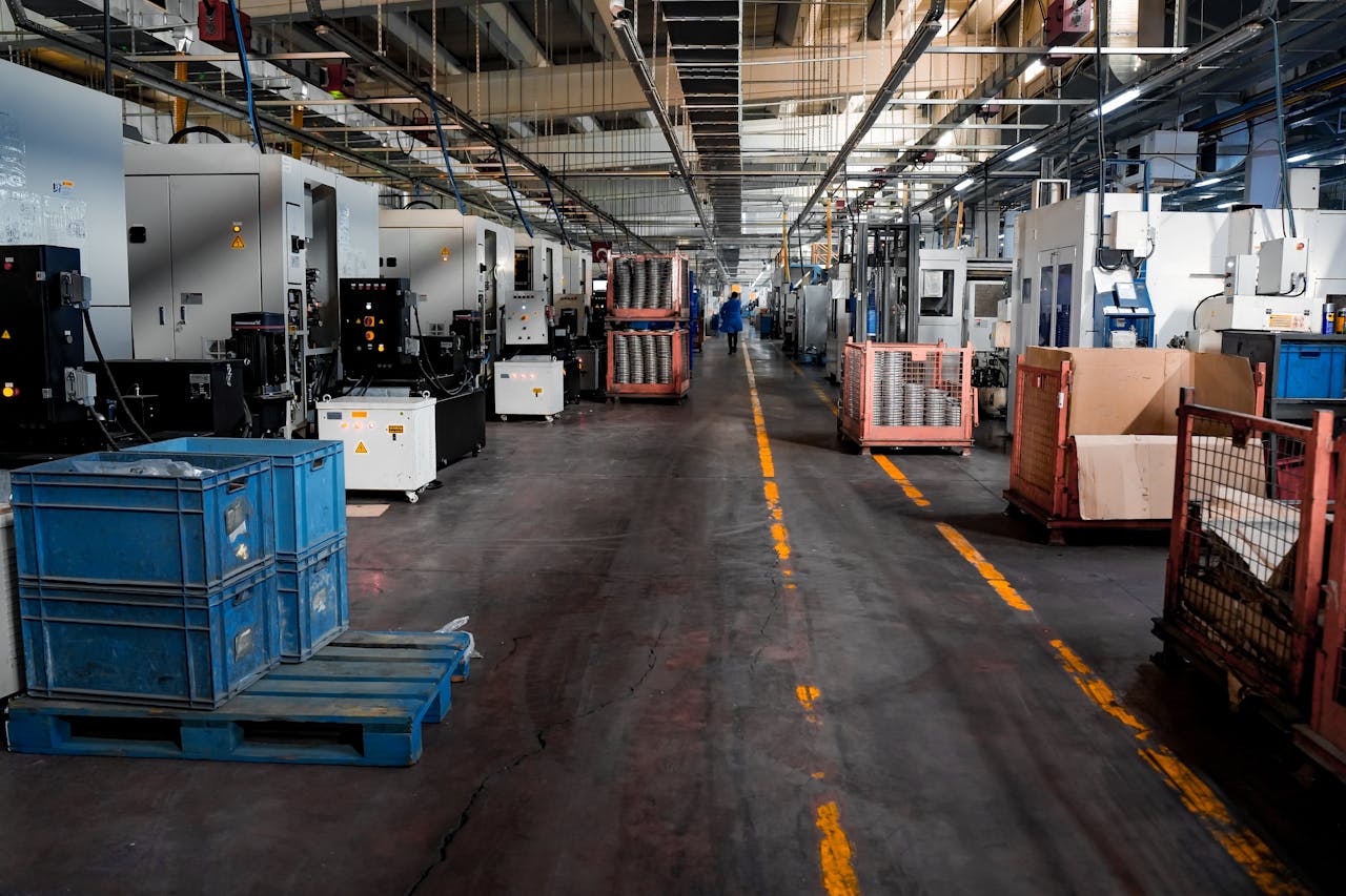 Vast industrial factory floor with machinery, crates, and structured workstations.